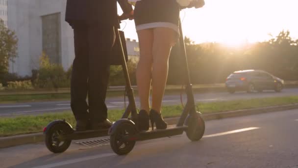 FECHAR UP: Jovens parceiros de negócios estão montando seus scooters elétricos ao nascer do sol . — Vídeo de Stock