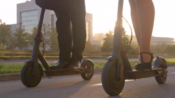 LENS FLARE: Gouden zonnestralen schijnen op medewerkers rijden elektrische scooters om te werken — Stockvideo