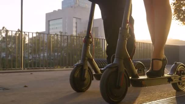 CERRAR Empresa y colega montar scooters eléctricos por una calle iluminada por el sol — Vídeos de Stock