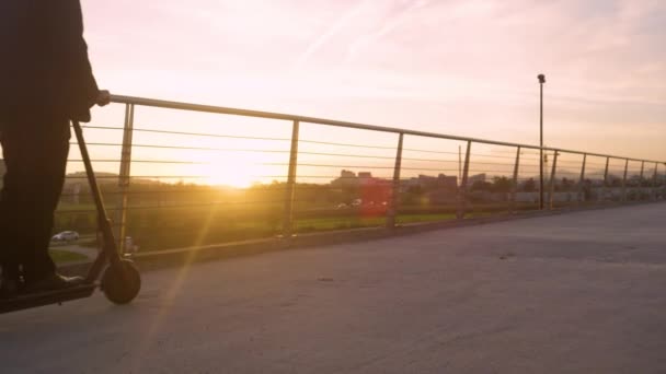 LENS FLARE: Joven hombre de negocios disfruta de un paseo en scooter a casa en el hermoso atardecer. — Vídeo de stock