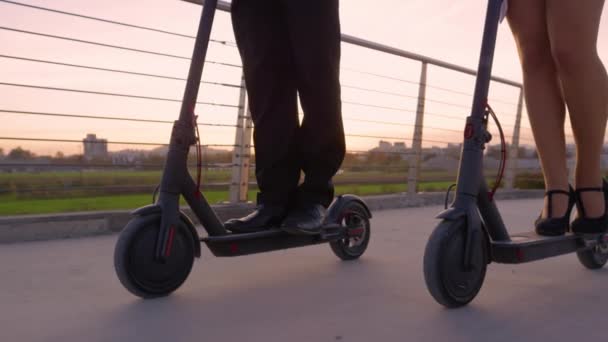 LENS FLARE: Colegas no desgaste formal passeio scooters elétricos para trabalhar ao nascer do sol. — Vídeo de Stock