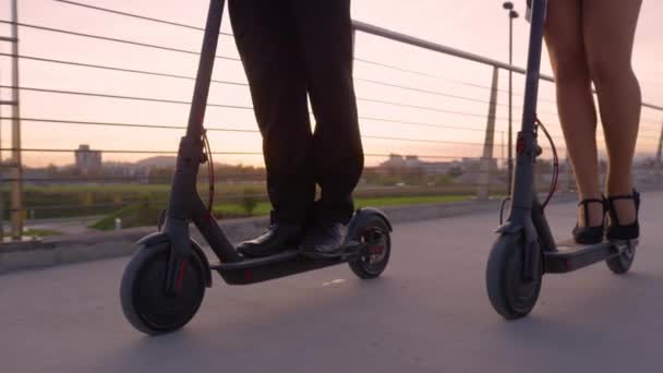 LOW ANGLE: Partnerzy biznesowi w formalnej przejażdżce na skuterach elektrycznych do pracy o wschodzie słońca. — Wideo stockowe