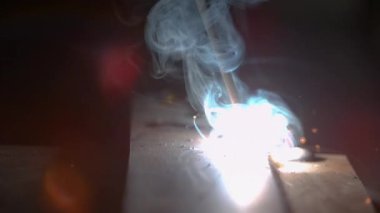Tanınamayan bir metal işçisi tarafından oluşturulan kaynak karanlık bir atölyede parlıyor..