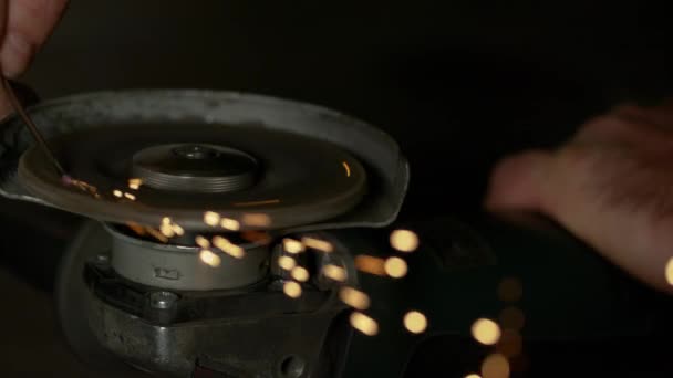 MACRO: Centelhas brilhantes voam de uma ferramenta de poder giratória moendo uma peça de trabalho de ferro . — Vídeo de Stock
