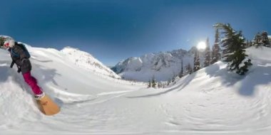 Ekstrem snowboardcu güneşli bir günde el değmemiş dağı oyuyor..