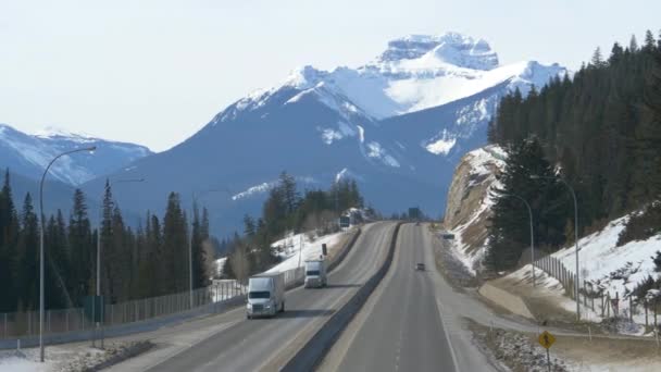 DRONE: Two cargo trucks drive down the Trans Canada Highway on sunny winter day. — Stock Video