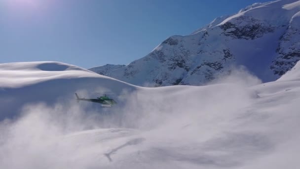 Grön helikopter lyfter och flyger mot de steniga bergen i fjärran — Stockvideo