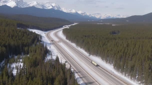 AERIAL: Ciężarówka przewozi ciężki czołg w dół malowniczej Trans Canada Highway — Wideo stockowe