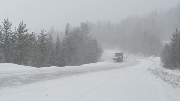 Truck plowing the road leads the way for traffic driving through a blizzard. — Stock Video