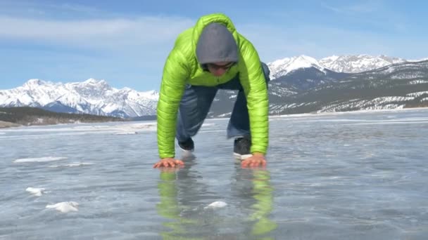 NAJNOWY Kąt: Człowiek walczący o zejście z śliskiej powierzchni zamarzniętego jeziora. — Wideo stockowe