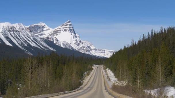 POV: Kör längs den tomma vägen och erbjuder utsikt över de snöiga kanadensiska klipporna — Stockvideo