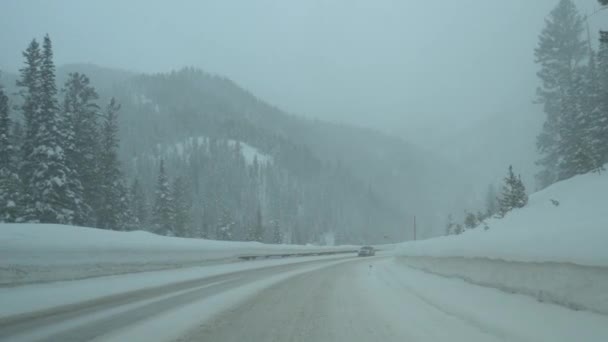 POV: Langs een andere auto door de besneeuwde auto rijden in de Rocky Mountains. — Stockvideo
