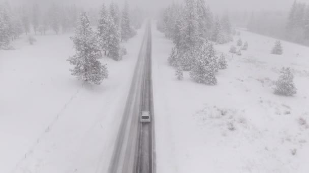 DRONE Літає за автомобілем, що їде через снігову бурю, як комунальні приводи до роботи — стокове відео