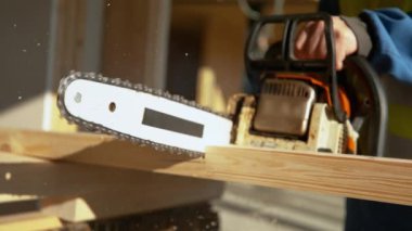 Tanımlanamayan işçi, kalası iki parçaya ayırmak için elektrikli testere kullanıyor..