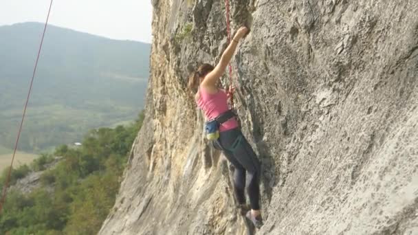 La escaladora femenina sin miedo escala un acantilado masivo en un día soleado de verano . — Vídeo de stock