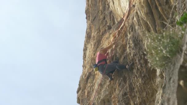 Jovem sem medo sobe um penhasco rochoso no dia perfeito para escalada — Vídeo de Stock