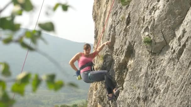 CERRAR: Impresionante toma de una mujer activa como ella roca sube por un acantilado masivo . — Vídeo de stock