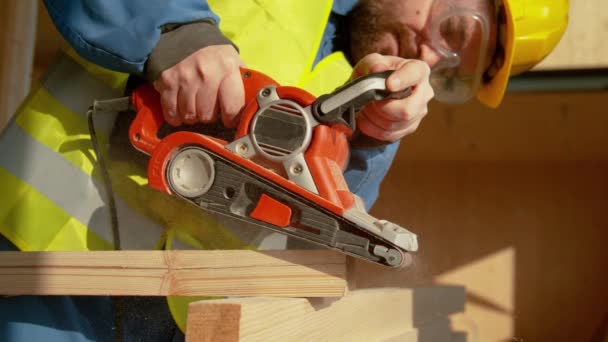 FERMETURE : Un entrepreneur expérimenté utilise une ponceuse pour lisser le bord d'une planche. — Video