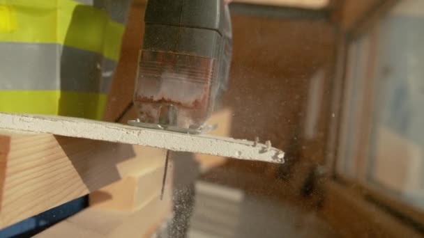 MACRO, DOF : Un constructeur méconnaissable coupe une plaque de plâtre avec un puzzle rouillé. — Video