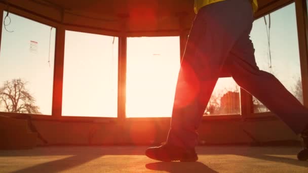 Il costruttore che viene al lavoro porta la cassetta degli attrezzi dall'altra parte della stanza all'alba. — Video Stock