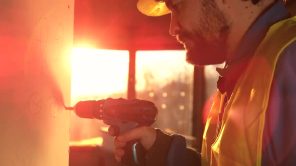 CLOSE UP LENS FLARE: Caucasian builder unscrews a bolt stuck in a wall panel. — Stock Video