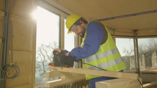 STÄNGA UPP: Små träbjälkar faller på marken när entreprenören försöker slipa den. — Stockvideo