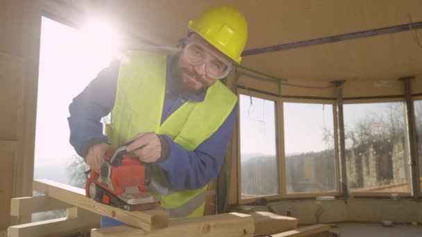 PORTRAIT, LENS FLARE: Bauarbeiter lächelt beim Schleifen eines Holzbalkens. — Stockvideo