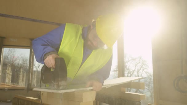 CLOSE UP, LENS FLARE: Contractor cuts up a plaster wall panel with a jigsaw. — Stock Video