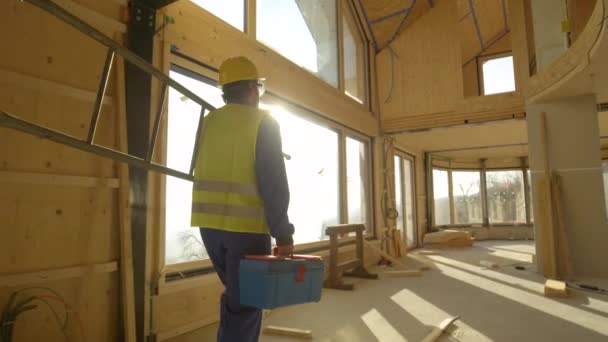 FERMER : Rayons de soleil dorés brillent sur le travailleur qui vient travailler dans une maison préfabriquée — Video