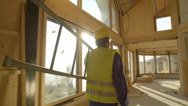 LENS FLARE Travailleur en salopette et casque de sécurité arrive au travail le matin ensoleillé — Video