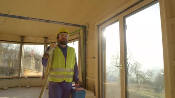 GESCHLOSSEN: Mann in blauem Overall und gelbem Bollenhut verlässt Baustelle — Stockvideo