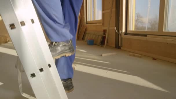 FERMER : Gros plan sur les jambes du travailleur qui monte une échelle en aluminium. — Video