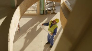 Statik mühendisi kat planlarına bakar ve evi gözlemler..