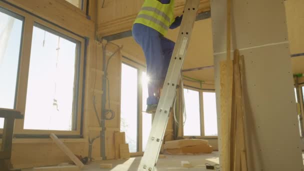 LOW ANGLE: Bouwer klimt van trapladder geplaatst in geprefabriceerd huis — Stockvideo