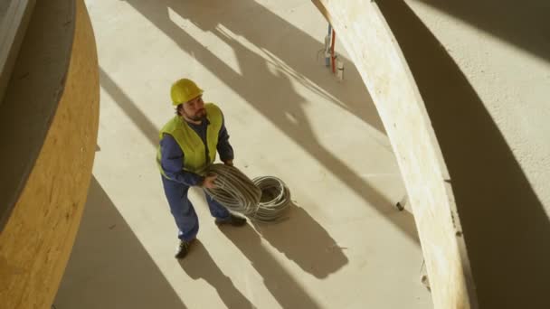 SLOW MOTION Arbeiter werfen Rollen von Kunststoff-Elektroleitungen eine Etage höher — Stockvideo