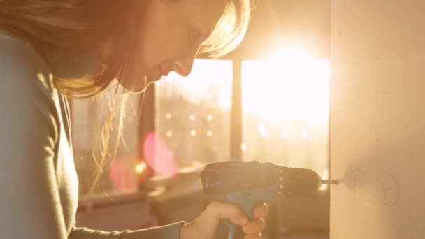 CLOSE UP: Woman uses a power drill to unscrew bolts out of a gypsum wall board — Stock Video