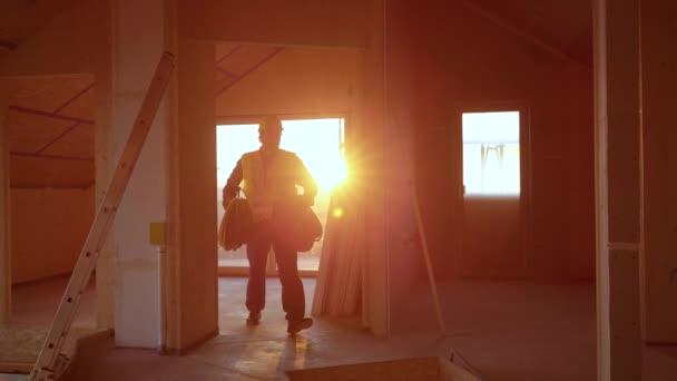 LENS FLARE: Stavitel přenáší válce hadic po podlaze ve výstavbě — Stock video