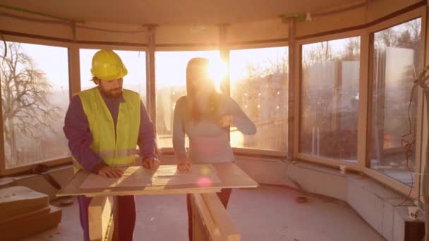 CLOSE UP: Ung kvinnlig entreprenör argumenterar med arbetstagare över byggplaner. — Stockvideo