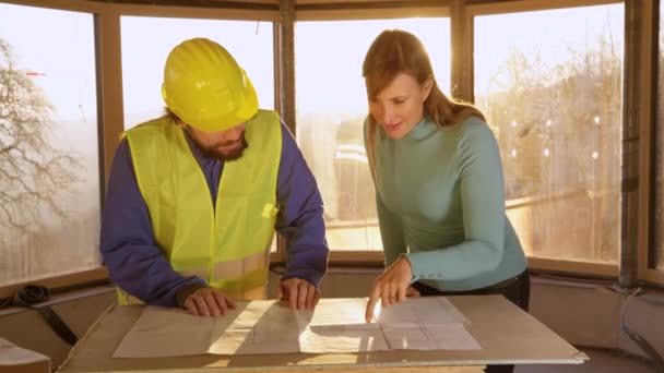 Lakástulajdonos és építész találkoznak napkeltekor, hogy megvitassák a tervrajzokat.. — Stock videók