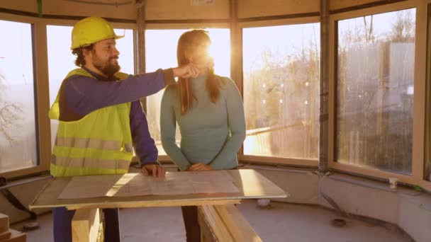 FERMER Jeune femme écoute l'entrepreneur expliquer ses plans d'étage pour sa maison — Video