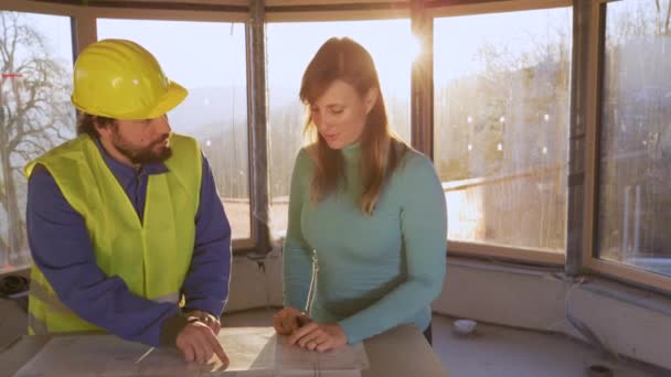 Жінка потискує руки інженерові після обговорення плану підлоги. — стокове відео