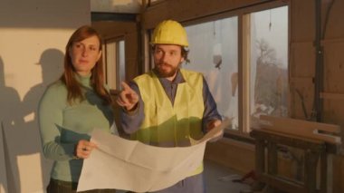 Mimar, inşaatın planlarını müstakbel genç ev sahibine açıklıyor..