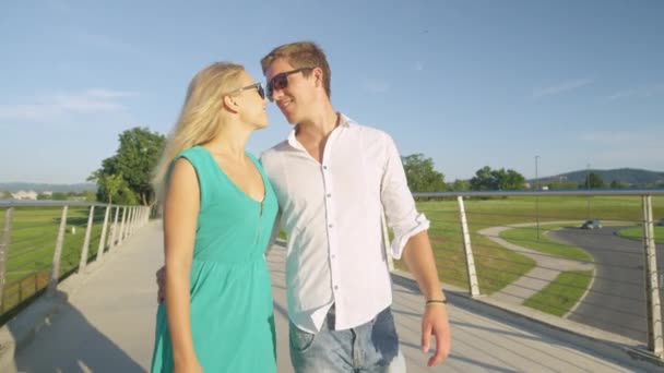 CLOSE UP: ciuman manis pasangan saat berjalan di jembatan pada hari yang cerah. — Stok Video