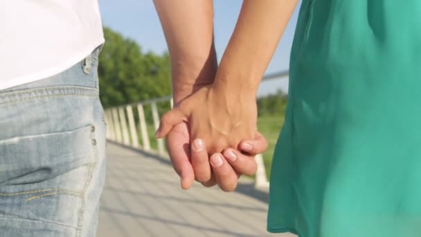 Close-up van de handen van het paar als ze gaan voor een romantische wandeling in het park — Stockvideo