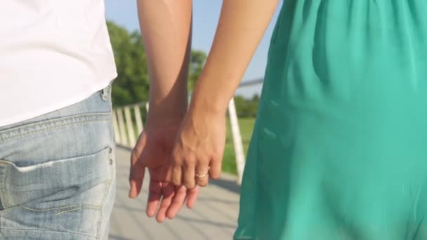 Az eljegyzési gyűrűjét viselő nő fogja a vőlegénye kezét séta közben. — Stock videók