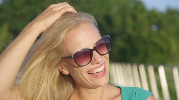 ZAMKNIJ SIĘ: uderzająco piękna dziewczyna śmieje się i bawi długimi blond włosami. — Wideo stockowe