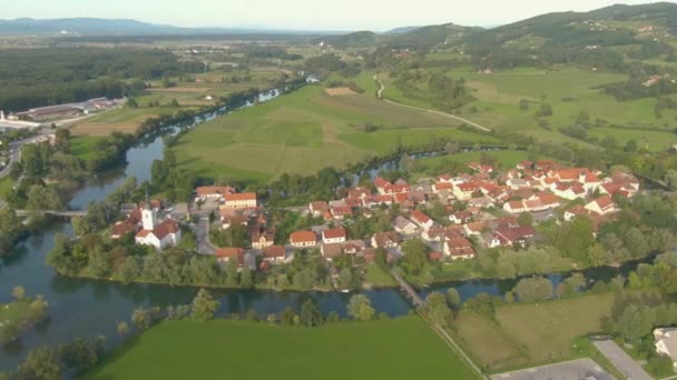 AERIAL: Voando sobre uma bela pequena aldeia construída em torno de um rio sinuoso. — Vídeo de Stock