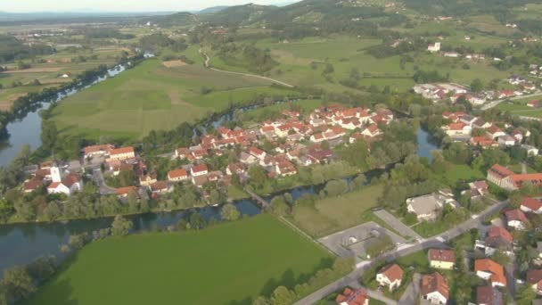 DRONE: Volando sopra un bellissimo piccolo villaggio costruito intorno a un fiume tortuoso. — Video Stock