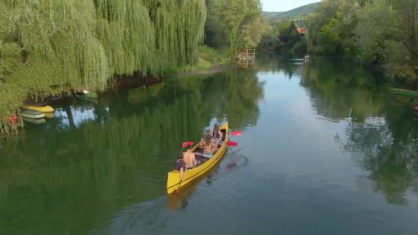 Sakin nehir boyunca büyük bir kanoyla kürek çeken bir grup arkadaşın üzerinde uçmak.. — Stok video