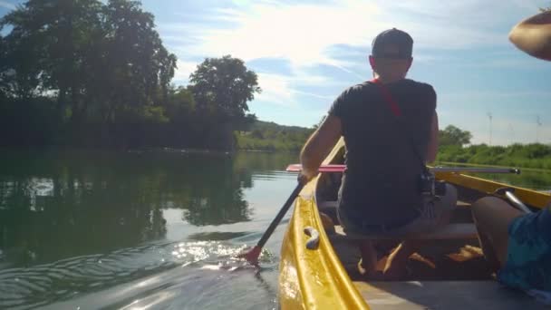 CLOSE UP: Junge Männer und Frauen paddeln mit einem Kanu auf einem ruhigen Fluss in Slowenien. — Stockvideo